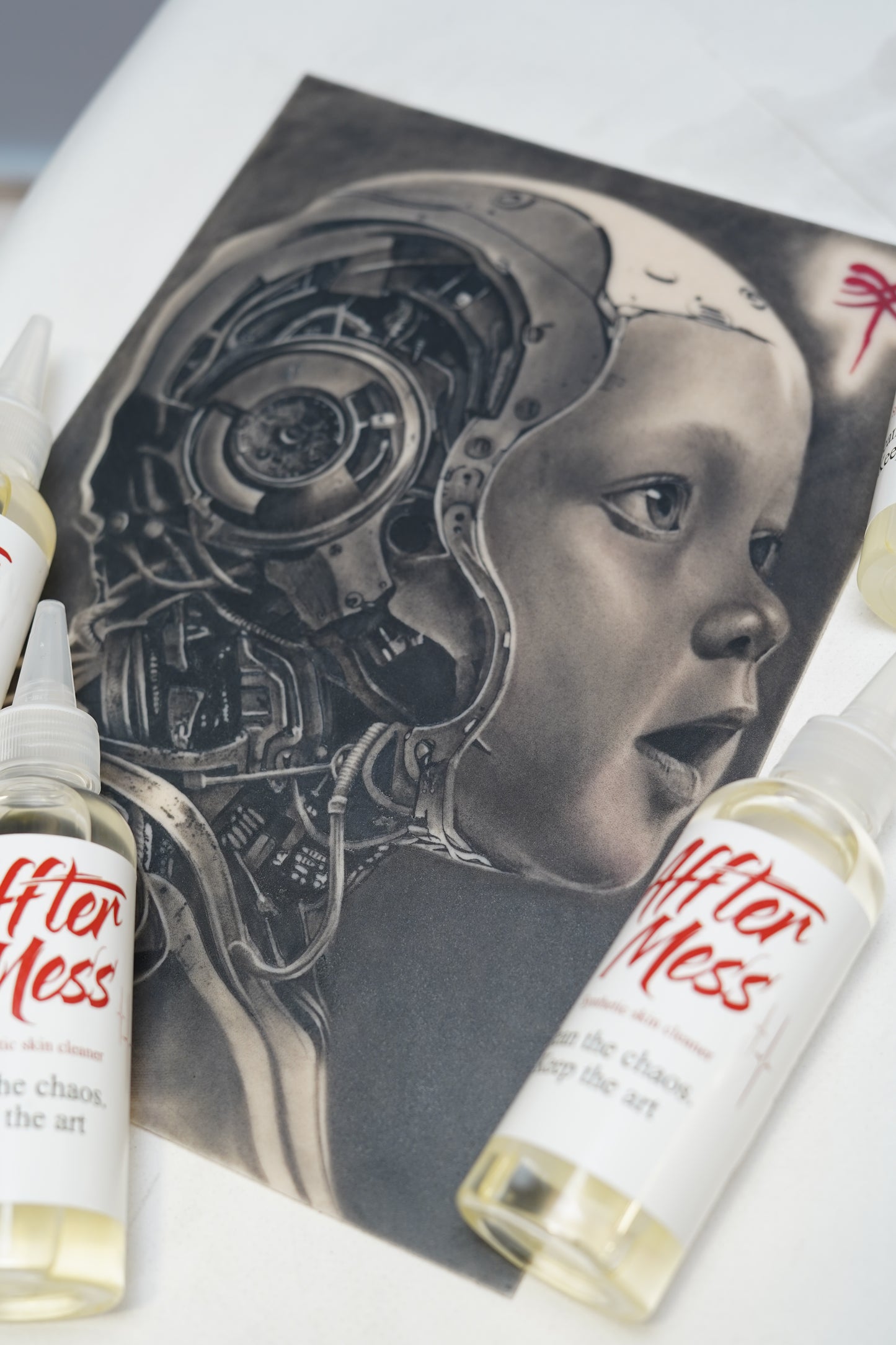Tattoo design of a mechanical head with 'After Less' products on a white surface